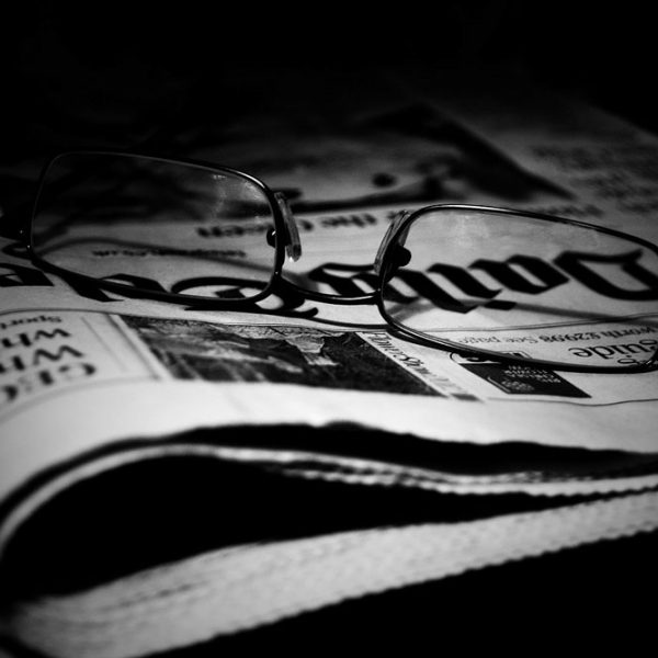 Brille auf einer Zeitung in dunkler Szenerie