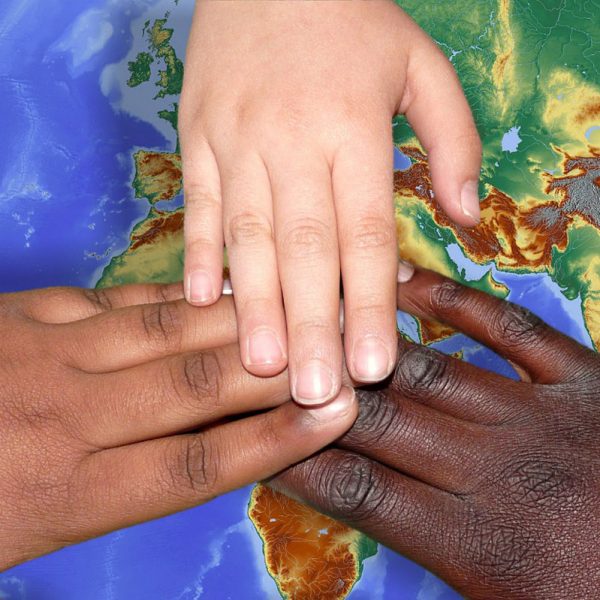 Hände unterschiedlicher Hautfarbe auf Weltkarte